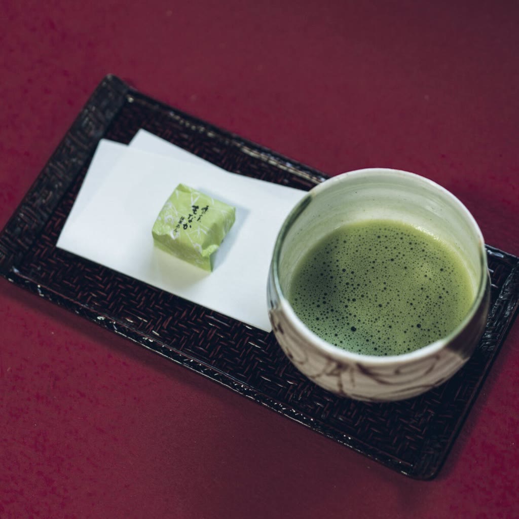 Bowl of whisked Yame matcha with a seasonal wagashi sweet on a lacquered tray